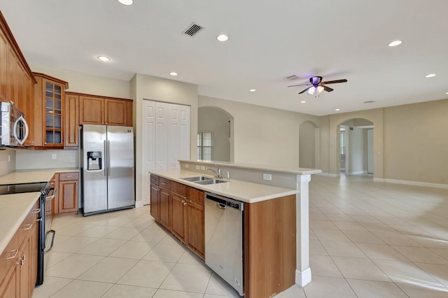 kitchen with light tile patterned floors, a center island with sink, ceiling fan, stainless steel appliances, and sink