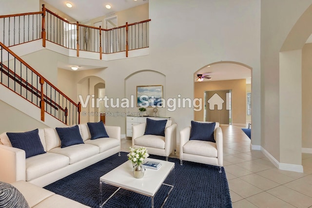 tiled living room featuring ceiling fan and a towering ceiling