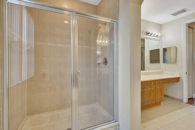 bathroom with a shower with shower door, vanity, and tile patterned flooring