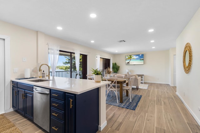 kitchen featuring kitchen peninsula, light wood-type flooring, dishwasher, blue cabinets, and sink