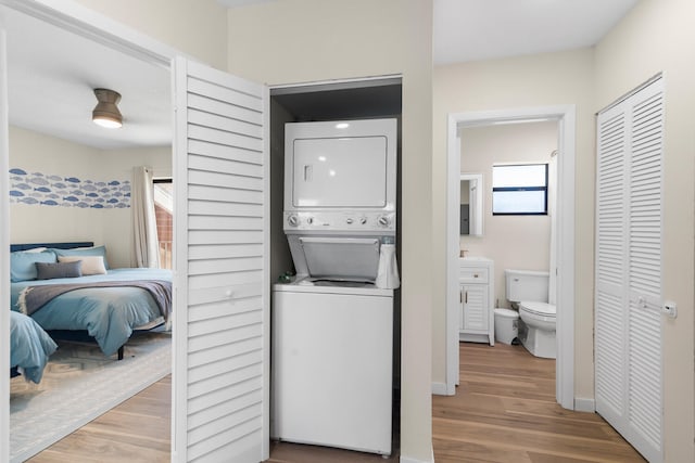 clothes washing area featuring stacked washer / dryer and hardwood / wood-style flooring