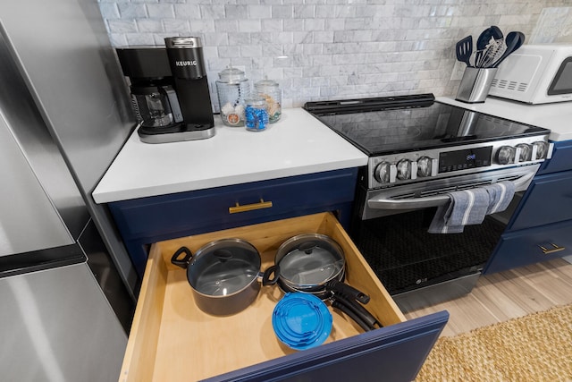 kitchen featuring decorative backsplash, blue cabinetry, and stainless steel range with electric cooktop