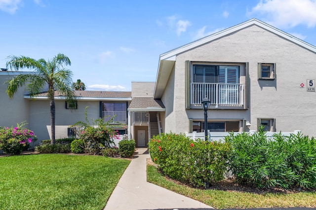 view of front of house with a front yard and a balcony