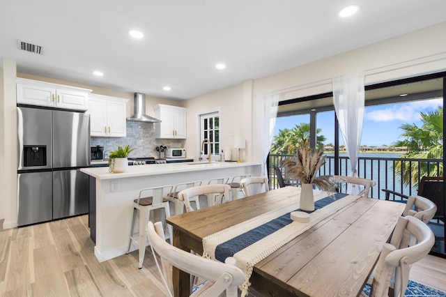 dining room with a water view, light hardwood / wood-style flooring, and sink