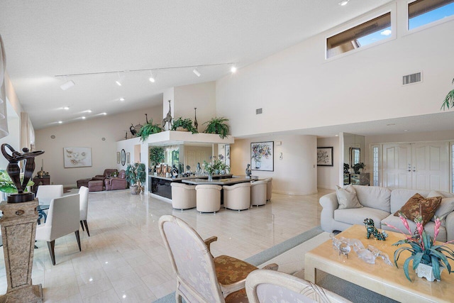 tiled living room featuring a textured ceiling and a towering ceiling