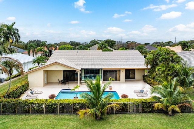 rear view of house featuring a fenced in pool, a patio, and a lawn