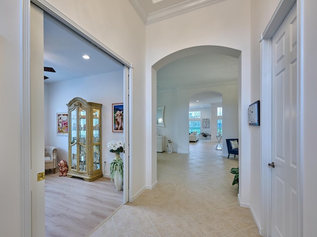 corridor featuring light tile patterned floors and crown molding