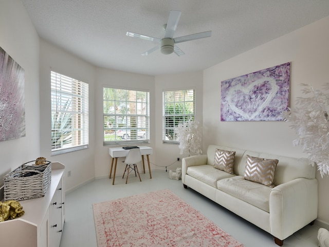 living room featuring ceiling fan, a textured ceiling, and a healthy amount of sunlight