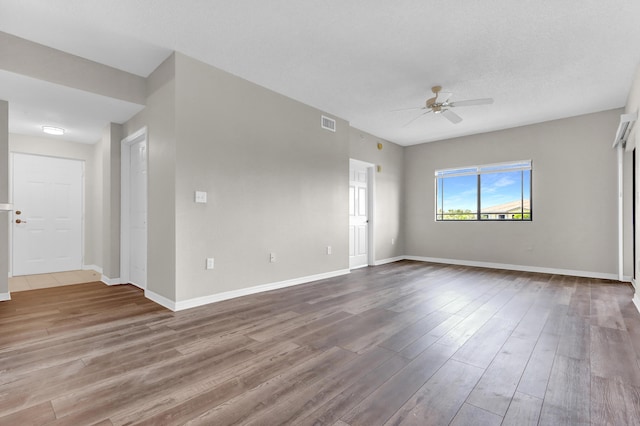 empty room featuring ceiling fan, hardwood / wood-style floors, and a textured ceiling