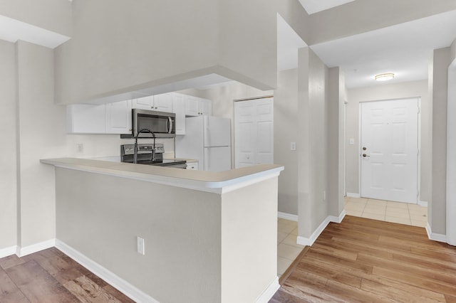 kitchen featuring kitchen peninsula, stainless steel appliances, light hardwood / wood-style floors, and white cabinets