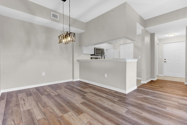 unfurnished living room with a notable chandelier and light wood-type flooring