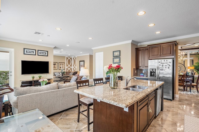 kitchen featuring sink, crown molding, appliances with stainless steel finishes, an island with sink, and a breakfast bar area