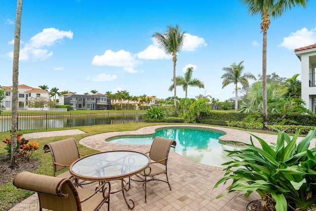 view of swimming pool featuring a hot tub, a water view, and a patio