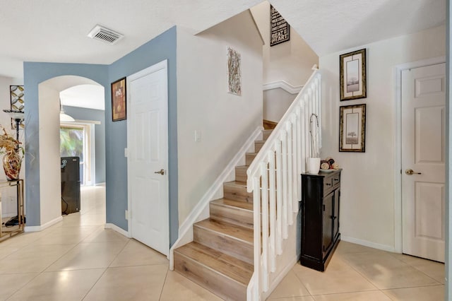 stairs with tile patterned floors and a textured ceiling