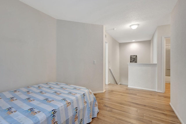 bedroom with a textured ceiling and light hardwood / wood-style flooring