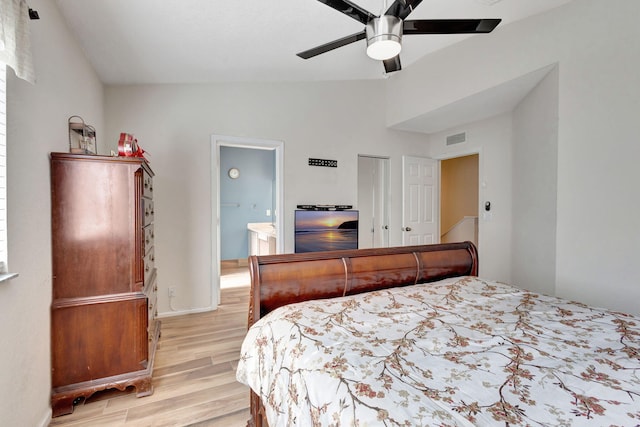 bedroom featuring light wood-type flooring, ceiling fan, ensuite bathroom, and vaulted ceiling