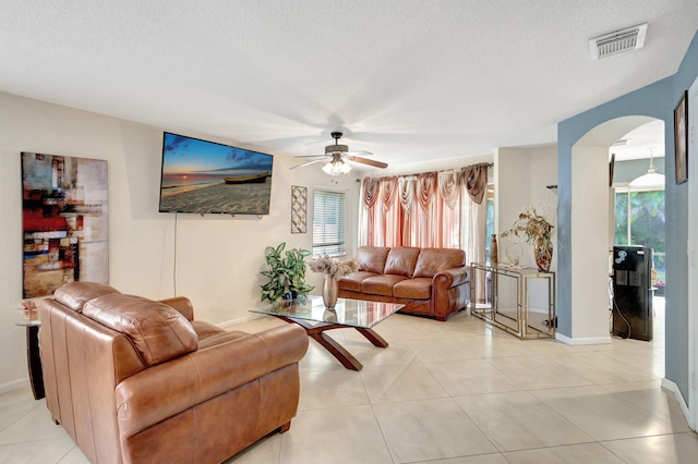 living room with a textured ceiling, ceiling fan, and light tile patterned floors