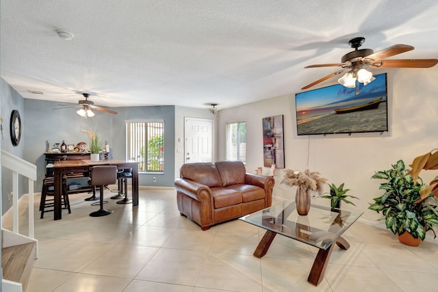 tiled living room featuring ceiling fan and a textured ceiling