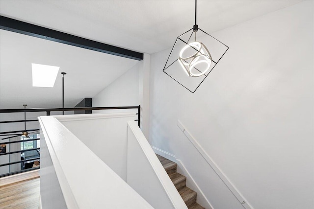 stairway with vaulted ceiling with skylight and hardwood / wood-style floors