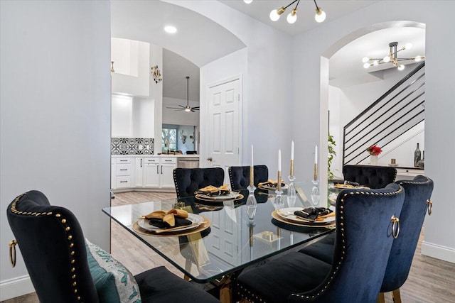 dining space with ceiling fan with notable chandelier and light wood-type flooring