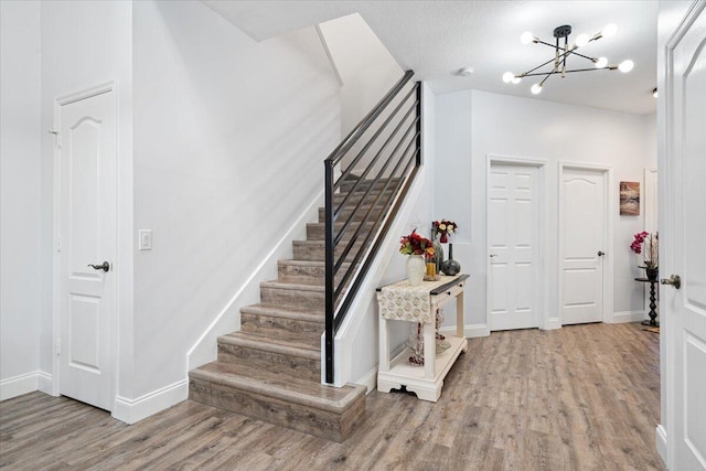 stairs featuring hardwood / wood-style floors, a notable chandelier, and a textured ceiling