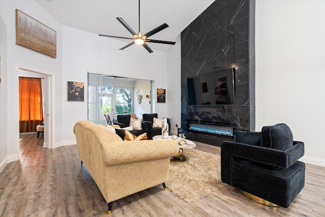 living room featuring hardwood / wood-style flooring, a high end fireplace, high vaulted ceiling, and ceiling fan