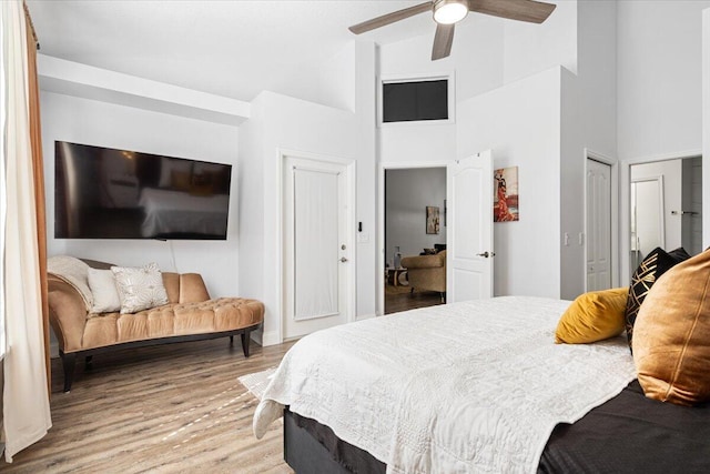 bedroom featuring ceiling fan, a high ceiling, and light wood-type flooring