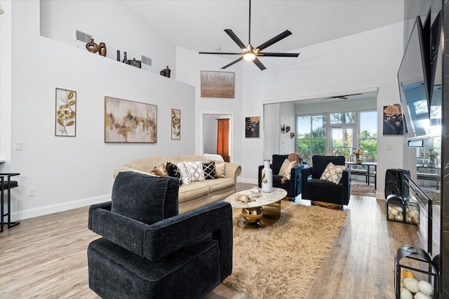 living room featuring a high ceiling, ceiling fan, and light hardwood / wood-style flooring