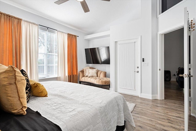 bedroom featuring hardwood / wood-style flooring, ceiling fan, vaulted ceiling, and a textured ceiling