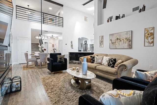 living room with hardwood / wood-style flooring, a chandelier, and a high ceiling