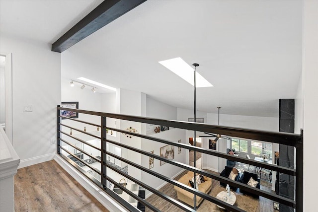 interior space with ceiling fan, beam ceiling, a skylight, and wood-type flooring