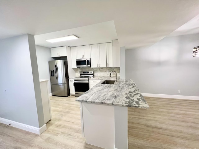 kitchen with tasteful backsplash, sink, white cabinetry, stainless steel appliances, and light stone counters