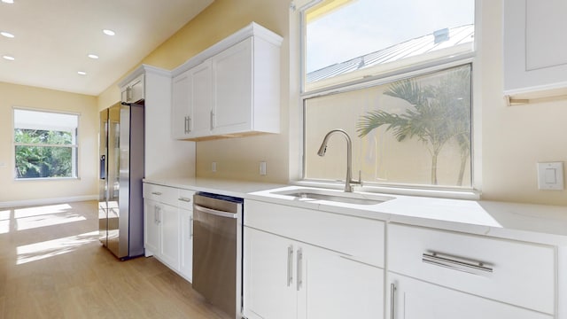 kitchen featuring sink, light hardwood / wood-style flooring, light stone countertops, appliances with stainless steel finishes, and white cabinets