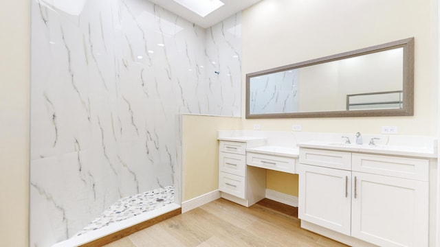 bathroom with vanity, a skylight, wood-type flooring, and tiled shower