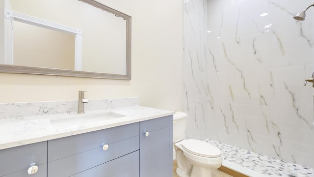 bathroom with tiled shower, vanity, and toilet