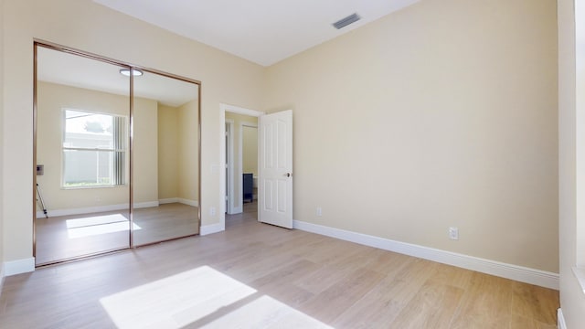 unfurnished bedroom with light wood-type flooring and a closet