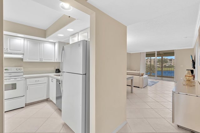 kitchen with a wall of windows, white cabinets, light tile patterned floors, and white appliances