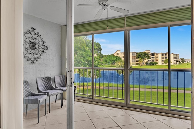 sunroom featuring ceiling fan and a water view