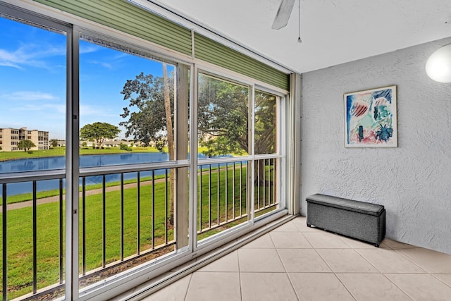 unfurnished sunroom with ceiling fan and a water view