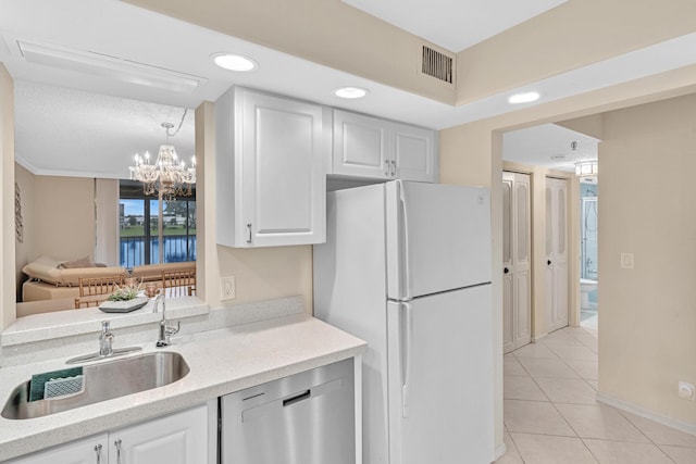 kitchen featuring white refrigerator, stainless steel dishwasher, white cabinets, and sink