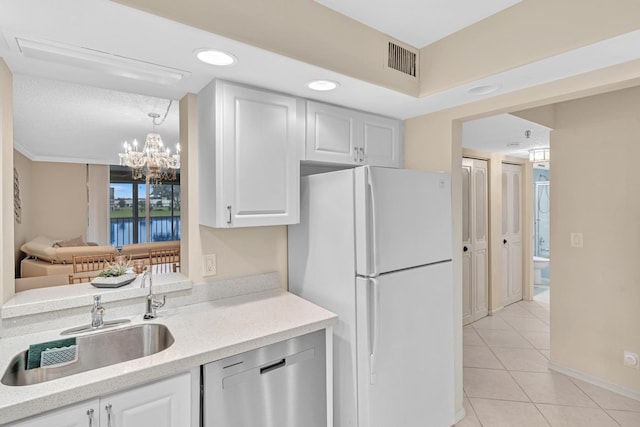 kitchen featuring dishwasher, sink, white fridge, and white cabinetry