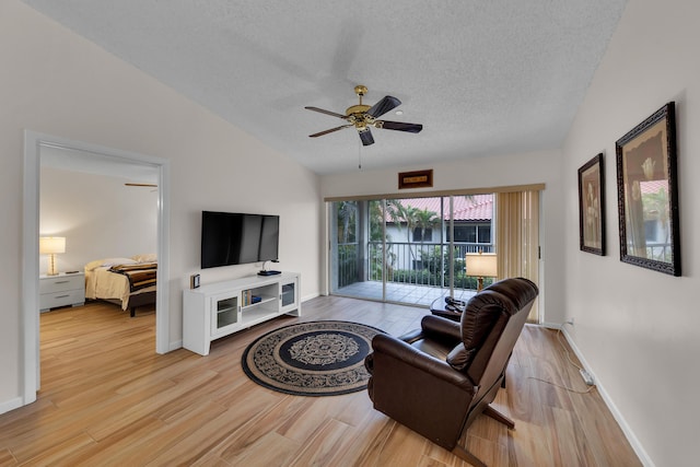 living room with ceiling fan, light wood-type flooring, vaulted ceiling, and a textured ceiling