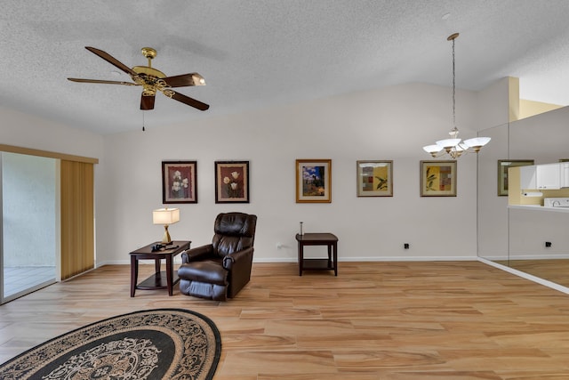 sitting room featuring a textured ceiling, lofted ceiling, ceiling fan with notable chandelier, and light hardwood / wood-style flooring