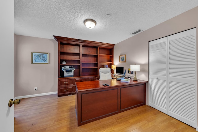 home office featuring a textured ceiling and light hardwood / wood-style floors