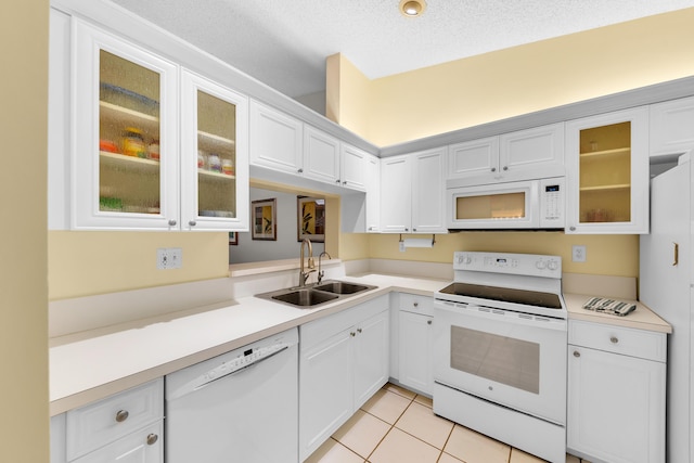 kitchen featuring white appliances, white cabinets, a textured ceiling, sink, and light tile patterned flooring