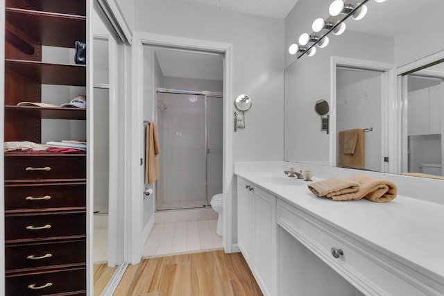 bathroom featuring wood-type flooring, an enclosed shower, vanity, and toilet