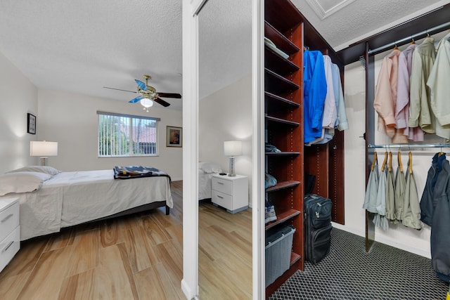 bedroom with ceiling fan, light hardwood / wood-style floors, and a textured ceiling