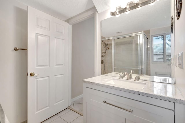 bathroom featuring a textured ceiling, tile patterned floors, a shower with shower door, and vanity