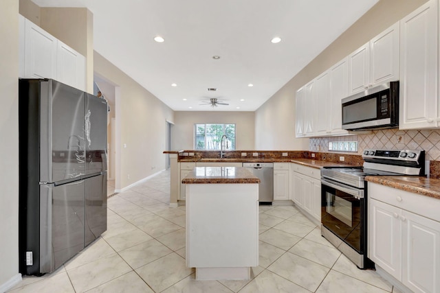 kitchen featuring ceiling fan, stainless steel appliances, a center island, white cabinets, and sink