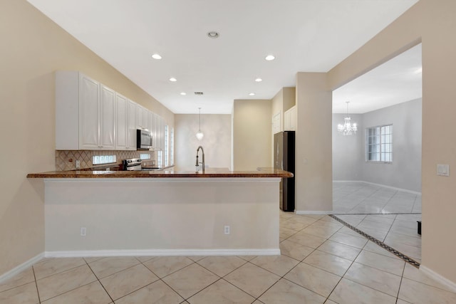 kitchen featuring white cabinets, appliances with stainless steel finishes, decorative light fixtures, kitchen peninsula, and light tile patterned floors